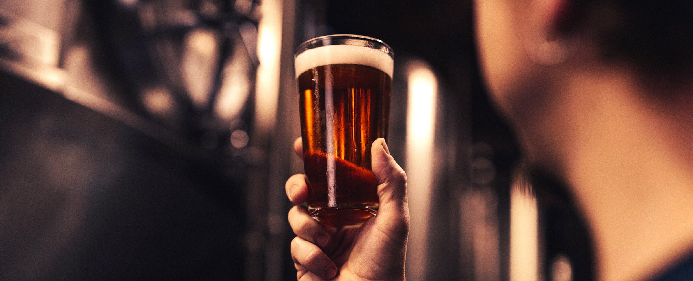 Ice cold craft beer in a glass in a mans hand.
